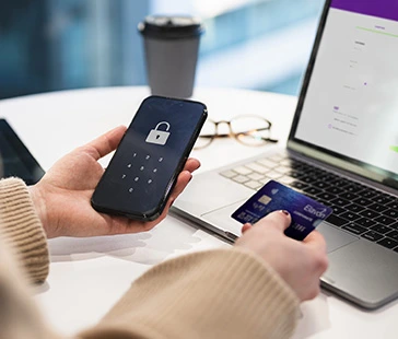 Person using a payment card and smartphone while setting up a secure recurring payment on a laptop