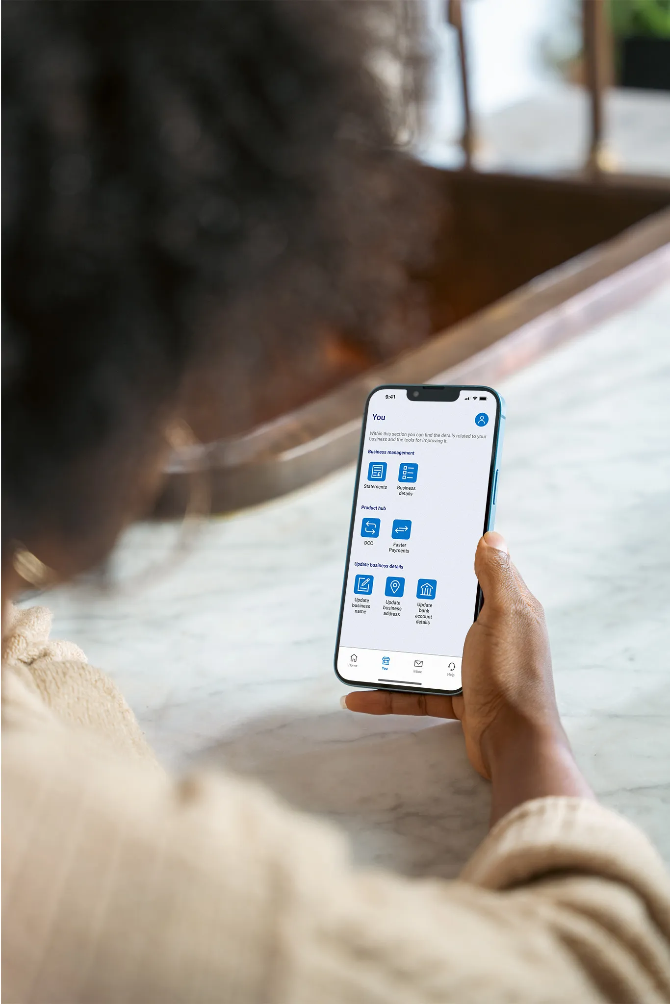 Person using the Elavon Connect mobile app to manage business details statements and payment services on a smartphone