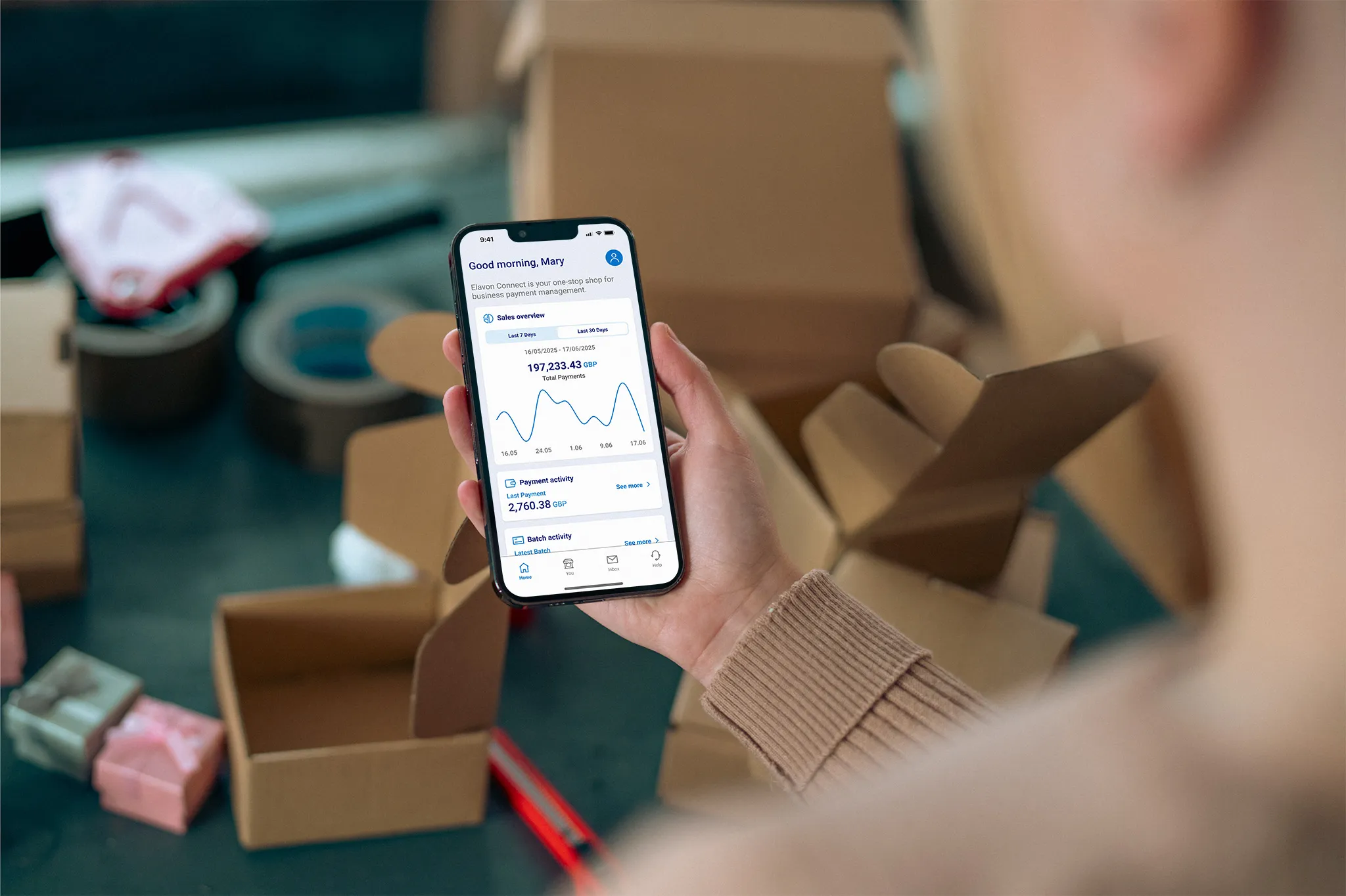 Person using the Elavon Connect mobile app to review sales and payment activity while packing customer orders